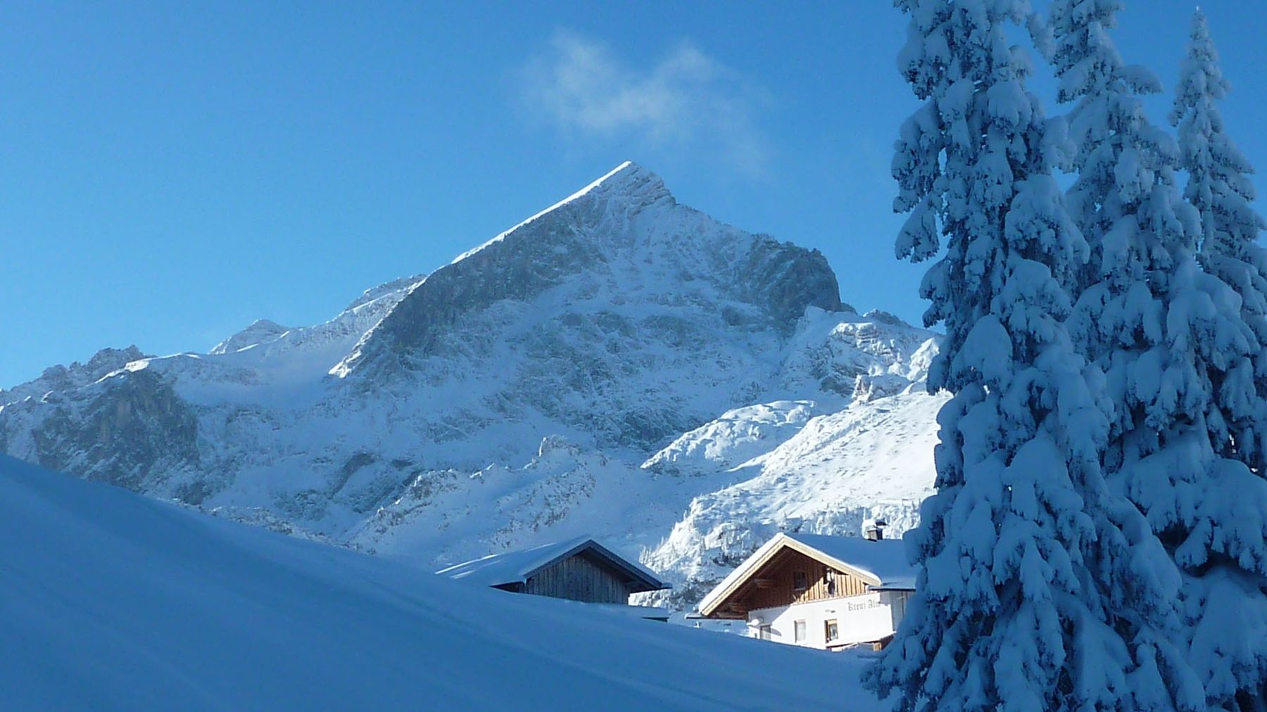 Die Alpspitze über verschneiten Almhütten im Winter